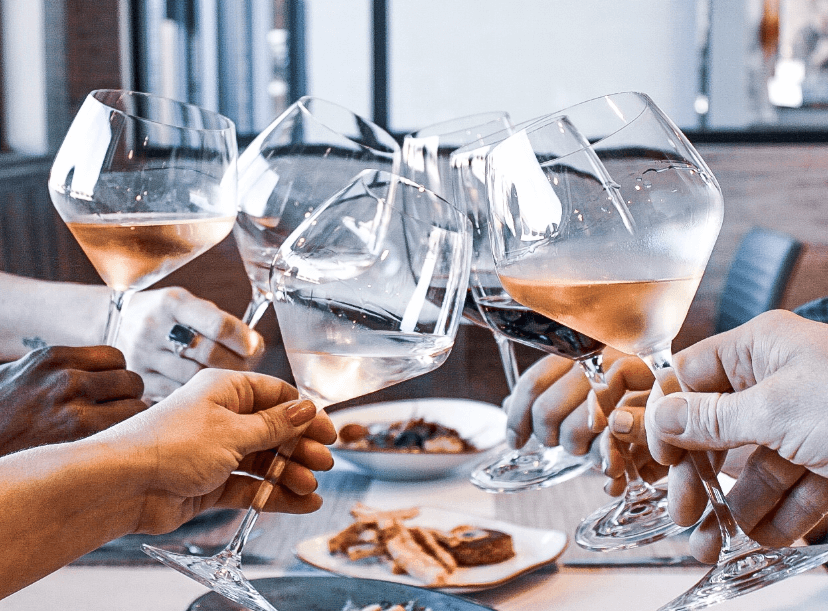 Wine glasses clinking in a toast, in celebration of the business selling at The Second Glass wine bar in Wilmington, North Carolina.